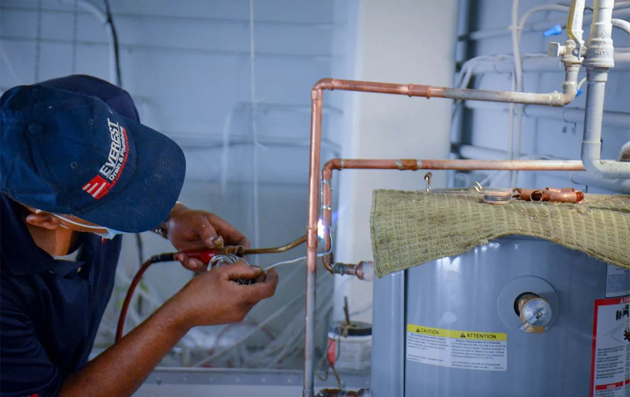 Licensed plumber repairing a leaking hot water tank.
