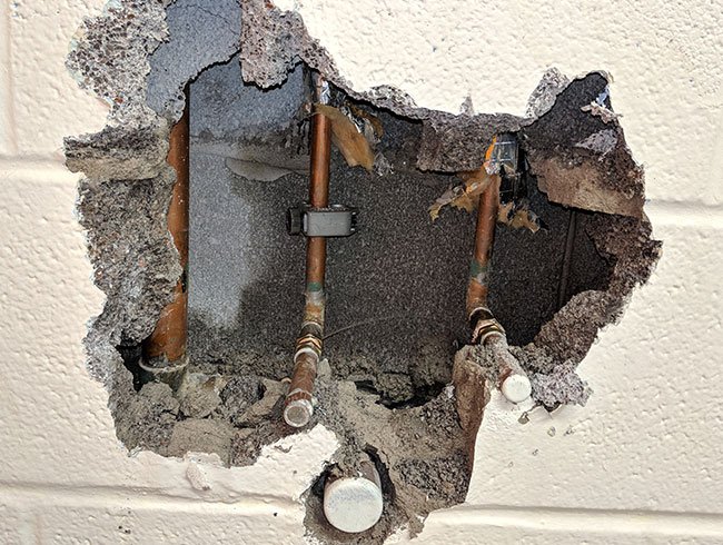 a hole in a wall with pipe for water leak detection